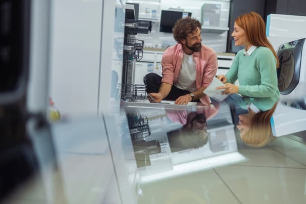 A smiling man and woman inspecting a dishwasher A smiling man and woman inspecting a dishwasher